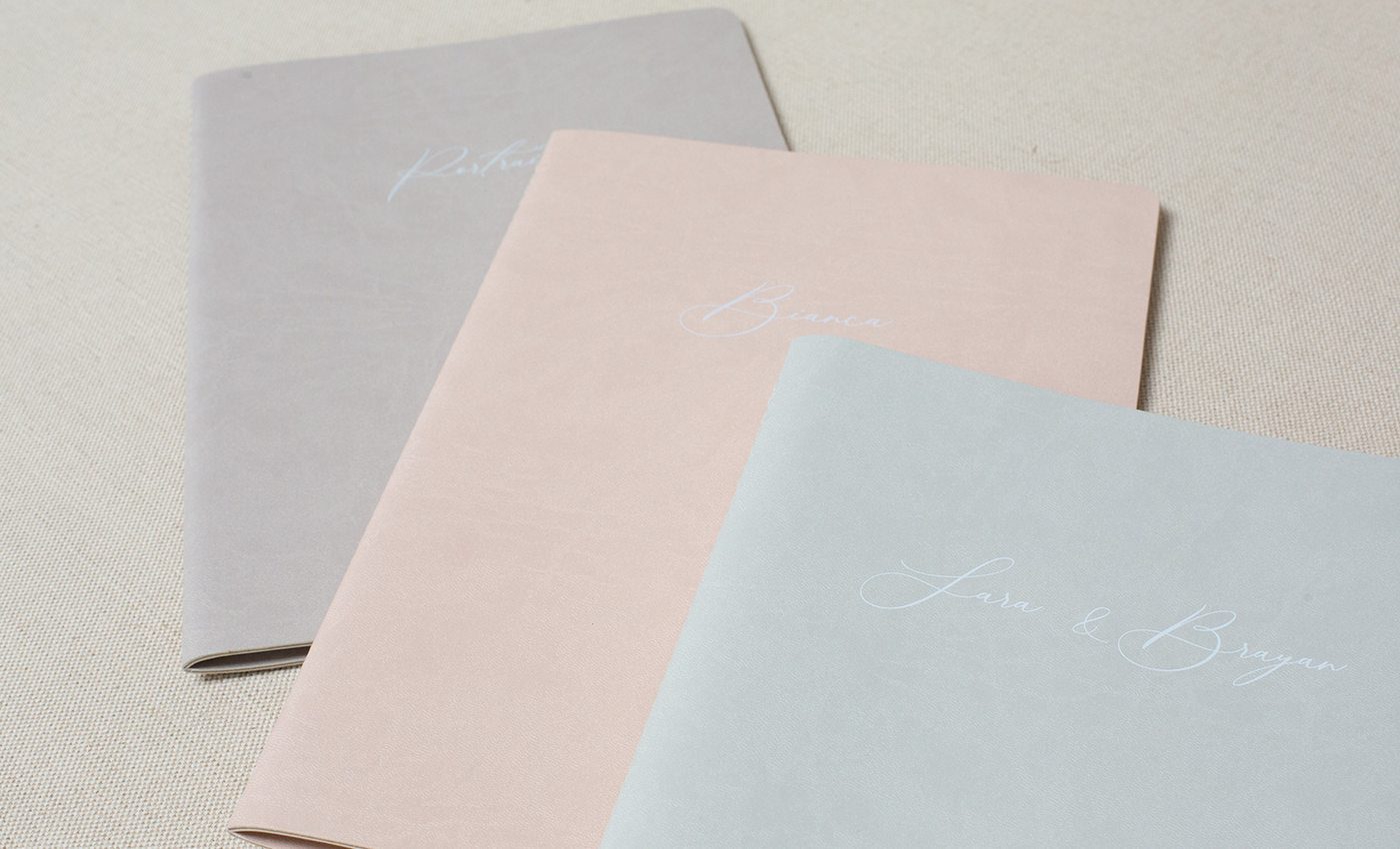 Three heirloom storybooks in different Cloud leatherette cover colors — warm grey, blush pink and sky blue